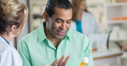 Man looking at bottle of medicine talking with pharmacist