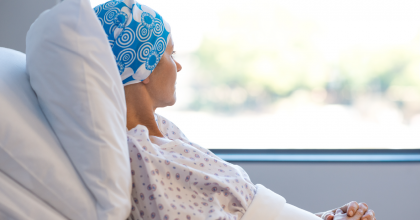 Woman laying on pillows in hospital bed looking out the window